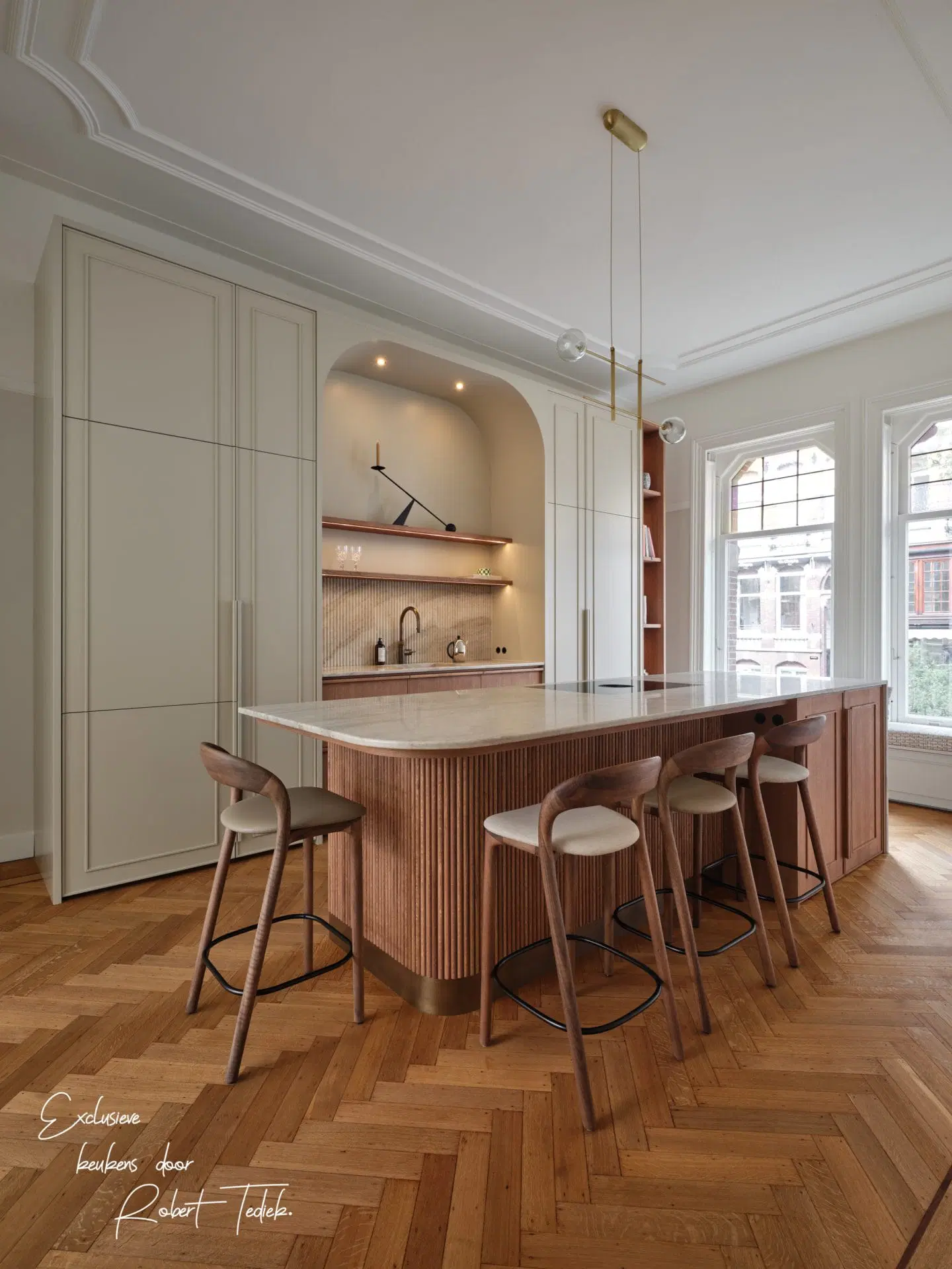 Fluted oak island with a stone top, off-white tall cabinetry and herringbone parquet