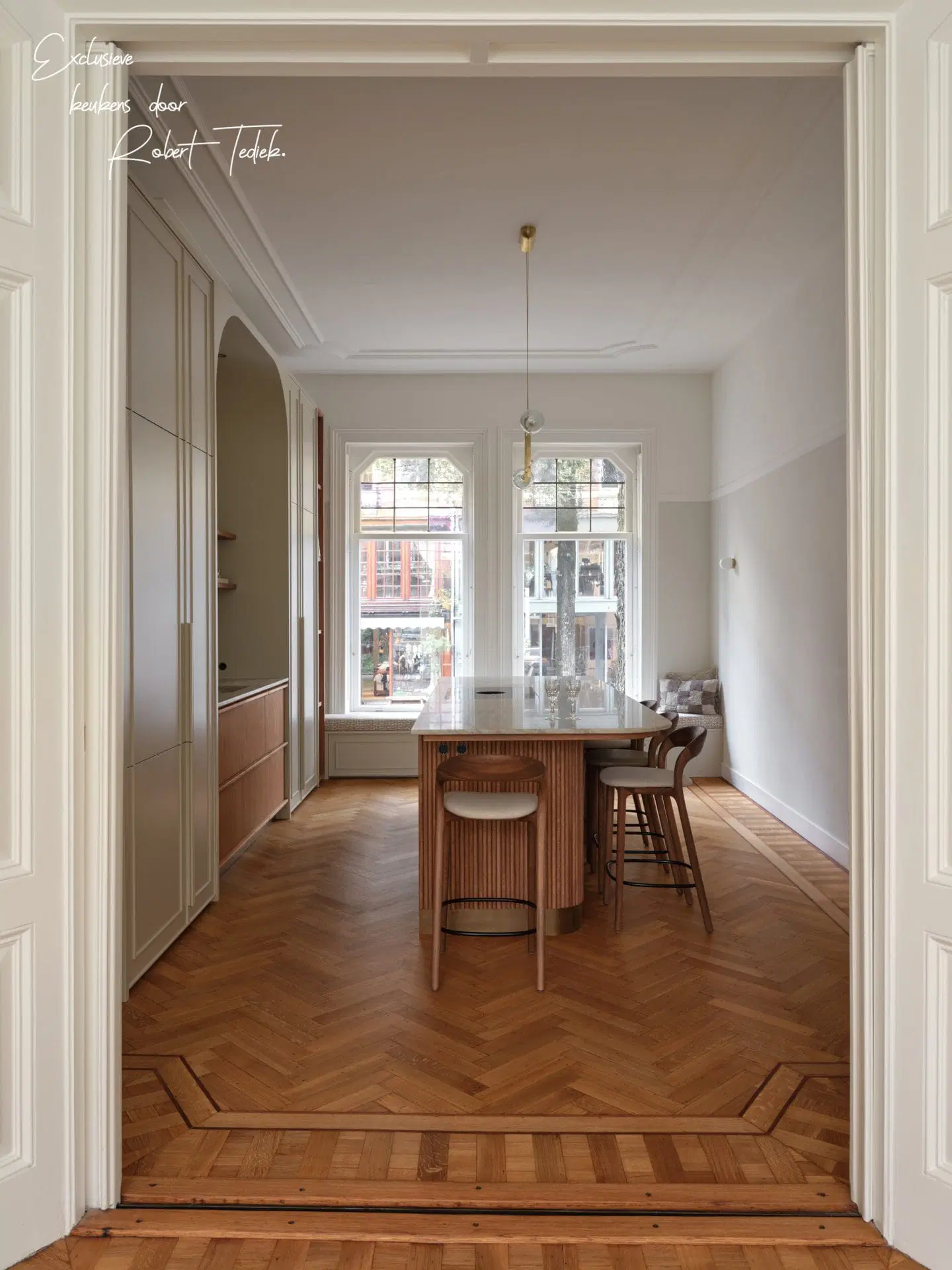 Kitchen room with tall white joinery, oak herringbone floor and moulded doorframes