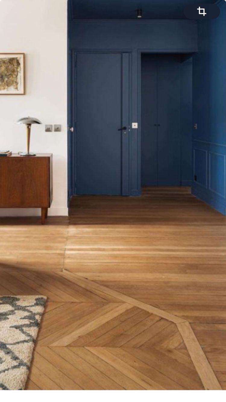 Hallway with doors and panelling painted the same deep blue, oak parquet floor