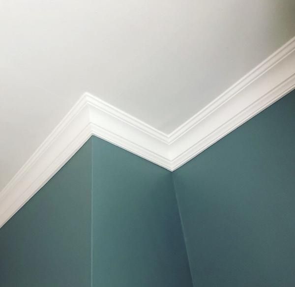 Teal painted wall meeting a white ceiling with a deep white crown moulding