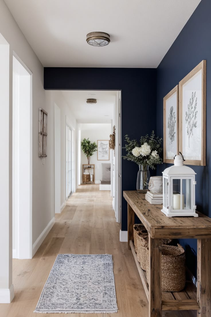Corridor with a navy accent wall, white joinery and a wide-plank oak floor