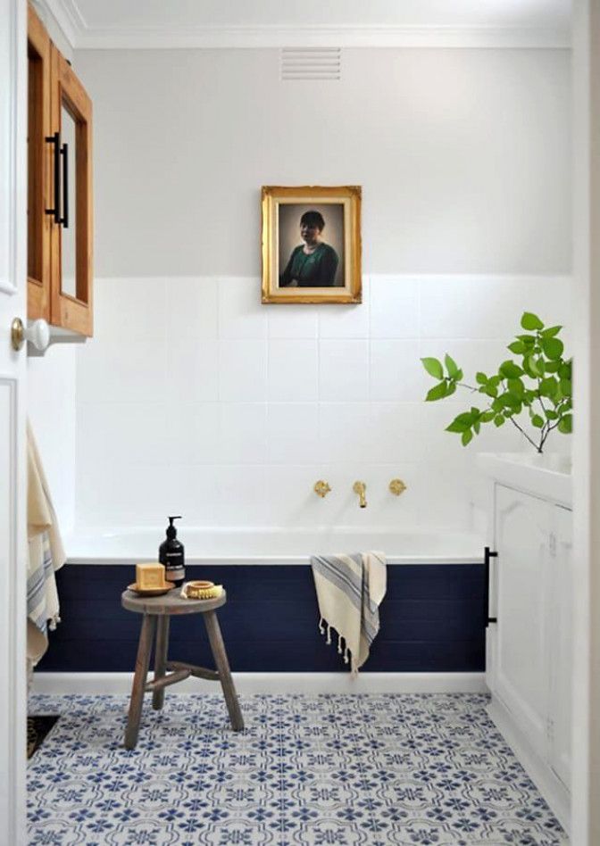 Bathroom with navy painted lower wall, white tiles above, brass taps and patterned floor tile